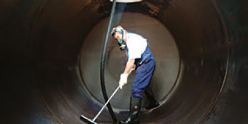 Wassertank nach der Umrüstung eines alten Öltanks - Mann in Schutzkleidung säubert einen Öltank